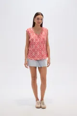 Blusa sin mangas con estampado geométrico en tonos rojo y blanco, de poliéster plisado, corte holgado y cuello redondo.