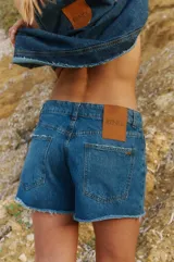 Short de jean azul con tiro medio, corte holgado y ruedo desflecado.