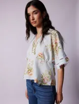Blusa celeste con estampado floral, escote en V, corte bajo busto y apliques de crochet en escote y mangas.