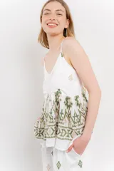 Blusa blanca de algodón con bordados artesanales en verde y corte suelto.