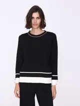 Sweater negro con botones en los puños y detalles en contraste en color blanco.