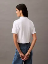 Remera corta de algodón blanco con textura acanalada, cuello polo con abertura y logo CK bordado en el pecho.