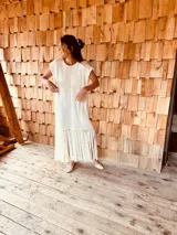 Vestido tejido color blanco con hilo metalizado, corte oversized, mangas cortas y flecos en el ruedo.