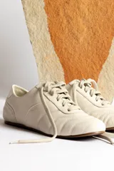 Zapatillas acordonadas color beige con detalles en blanco.