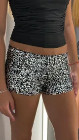 Shorts negros cubiertos completamente de lentejuelas plateadas, tiro bajo.