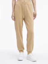 Pantalón de jogging color beige, de corte relajado, con cintura y tobillos elásticos, bolsillos laterales y logo pequeño en el lateral.