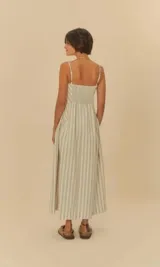 Vestido largo con rayas verticales en tonos beige y blanco, tirantes finos ajustables y escote cuadrado. Corte en A con movimiento fluido.