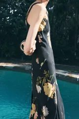Vestido largo negro con estampado floral en tonos naranja y blanco, escote en V y breteles finos.