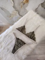 Conjunto de lencería de encaje verde musgo con detalles en beige, compuesto por un corpiño triangular sin aro y una tanga con tiras ajustables.