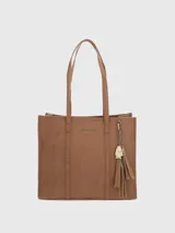 Cartera tote de cuero sintético color marrón, con doble asa de hombro y cierre superior. Incluye un dije colgante con el logo de la marca y flecos.
