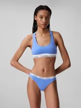 Conjunto Calvin Klein color celeste, compuesto por un corpiño deportivo con espalda racerback y una bombacha colaless. Ambos tienen cintura elástica blanca con el logo de la marca.