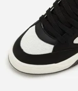 Championes urbanos de hombre, modelo street, color negro y blanco. Presenta capellada de material sintético (PU) con recortes, puntera redonda, cordones negros y paneles de malla blanca para ventilación. Posee una suela gruesa (bold) de color blanco y negro.