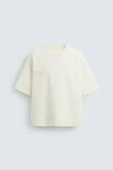 Camiseta color crema de corte recto, cuello redondo y mangas cortas. Estampado en relieve con la frase "Endless Skies".
