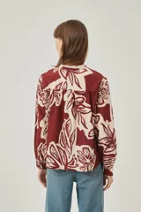 Camisa de poliéster con estampado floral en tonos borgoña y crema, corte holgado, cuello mao y cierre frontal con botones.