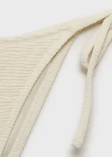 Braga de bikini blanca con textura, corte cheeky y lazos laterales.