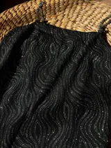 Vestido corto negro con estampado de líneas onduladas plateadas y tirantes de cadena metálica.
