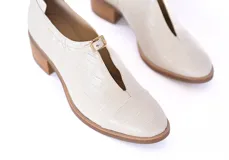 Zapato de cuero texturizado color blanco hueso, con punta cuadrada, detalle de hebilla dorada y taco de madera.