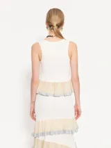 Top blanco sin mangas con detalle de volados plisados en el ruedo.