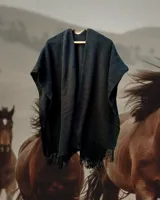 Ruana tejida en telar con lana merino 100% natural, color negro, con flecos en los bordes.