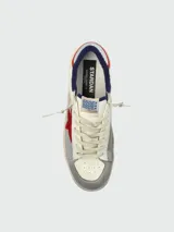 Zapatillas Golden Goose modelo Stradan, de cuero blanco con detalles en gris y rojo. Presentan una estrella roja de gamuza en el lateral, puntera de gamuza gris, detalles de mesh plateado y talón azul.