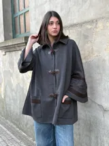 Saco tipo capa color gris de tejido de punto fino en lana con detalles de cintas tejidas y trenza.