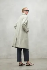 Chaqueta color beige, repelente al agua, con cuello clásico, cierre con botones, bolsillos laterales y corte holgado. Fabricada con poliéster reciclado y algodón orgánico.