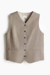 Chaleco de vestir color beige, con cuello en V, cierre de botones y bolsillos delanteros insertados. Forrado.