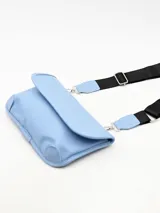 Bandolera azul pastel con correa ancha de tela negra ajustable.