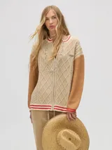 Saco estilo bomber color beige con mangas color ladrillo, tejido a rombos y ochos, con puños bicolor y cierre metalizado.