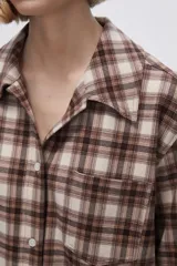 Camisa a cuadros marrón y beige de manga larga con cuello clásico y bolsillo en el pecho.