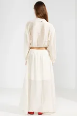 Blusa corta color crema en tejido arrugado liviano, con cuello mao, botones al frente y mangas abullonadas. Terminada con ruedo elastizado.