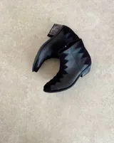 Botín de cuero vacuno color bronce con puntera y caña en cuero negro. Diseño con borde superior en zigzag y taco de madera.