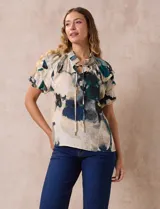 Blusa estampada con cuello fruncido y lazo, mangas cortas con volados.