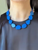 Collar corto con cuentas de piedra irregulares color azul y mostacillas azules. Se cierra con cadena de acero quirúrgico y gancho para regular el largo.