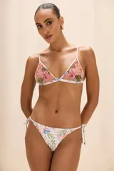 Braga de bikini de lycra color blanco con estampado de corales en tonos rosa, verde y azul. Presenta fruncido en la espalda y tirantes para atar a los lados con puntas doradas.