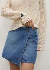 Short pollera de jean de tiro medio con diseño cruzado y cierre de botón.