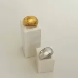 Anillo plateado con forma de domo y detalle de esfera dorada en un lateral.