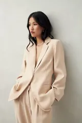 Blazer color beige con finas rayas verticales, de corte clásico y solapas de muesca.