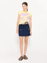 Conjunto de mini falda y chaqueta color crema con botones dorados y costuras en contraste.