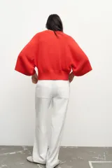Sweater de punto color naranja con cuello redondo y mangas anchas hasta el codo.