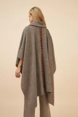 Poncho de lana color marrón con cuello alto, mangas 3/4 y bolsillo lateral con detalle de botones de cuero.