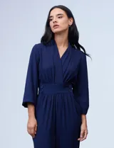 Enterito de gasa azul con escote en V cruzado, cintura con faja y botones, y espalda elastizada.