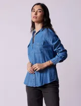 Camisa celeste de lyocell, marca Zac & Rachel. Cuello con solapa, abertura central con botones y bolsillos delanteros.