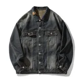 Campera de jean azul oscuro con corte boxy y efecto desgastado. Presenta detalles de roturas, cuello clásico, cierre frontal con botones metálicos y bolsillos de parche con solapa en el pecho.