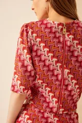 Top tejido de poliéster y viscosa con estampado abstracto en tonos rojo, naranja y blanco. Tiene mangas cortas abullonadas y cuello redondo.