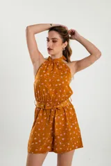 Mono de tirantes con estampado floral sobre fondo mostaza, de corte suelto y cinturilla ajustable.
