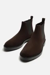 Bota Chelsea de cuero marrón oscuro con elásticos laterales negros, tirador trasero y suela plana.