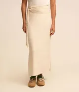 Pollera midi color crudo, de corte evasé y cintura media, confeccionada en viscosa con textura similar al lino. Presenta lazo lateral y fruncido.