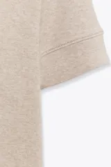 Remera color beige de corte recto, cuello redondo y mangas cortas con dobladillo.