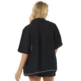 Camisa negra de manga corta con bordado de conchas marinas y motivos geométricos en blanco.